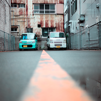 2 parked cars in an industrial looking area, in the streets of Japan