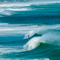 A lone surfer dwarfed by cyclonic waves at Coolum Beach