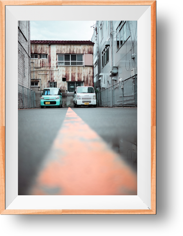 2 parked cars in an industrial looking area, in the streets of Japan